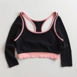 Pastel pink black long sleeve active top seamless sports bras folded neatly on a neutral surface, top-down view.