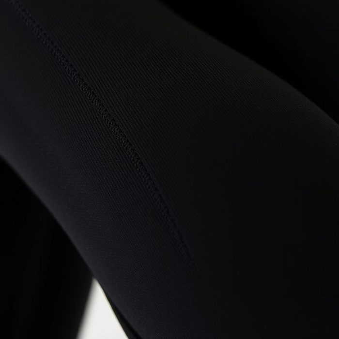Close-up of black yoga pants fabric showing moisture-wicking performance material and quality stitching for straight leg yoga pants.