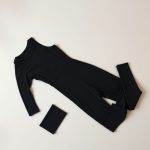 Black yoga jumpsuit with pocket leggings folded neatly on a neutral surface, flat lay top-down view.