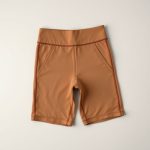 Flat lay of beige black cycling shorts leggings with pockets for women, neatly folded on a neutral surface.