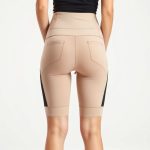 Back view of a model wearing black cycling shorts leggings with pockets in beige, studio shot on white background.