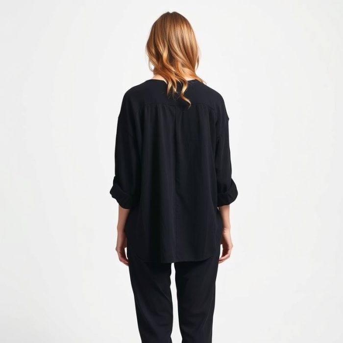 Back view of a model wearing the boho clothing brand chai loose leaf top in black, studio shot.