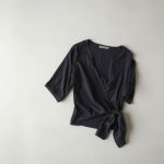 Charcoal organic cotton wrap top, neatly folded in a minimalist flat lay.