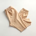 Flat lay of beige flare active pants sculpting dreams neatly folded on a neutral surface, top-down minimalist view.