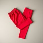 Red golf pant womens golf dresses neatly folded on a neutral surface, top-down flat lay view.
