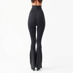 Back view of a model wearing high waisted flare leggings in charcoal, showcasing fit and pockets on pure white background.