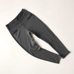 High waisted yoga pants in Heather Grey, neatly folded on a neutral surface, black leggings with pockets, top-down view.