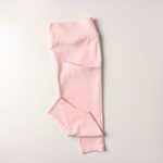 Flat lay of pastel pink sculpting leggings with pockets, neatly folded on a clean neutral surface.