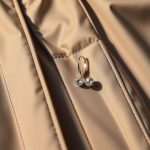 Close-up of moisture-wicking Performance Fabric in women's anorak jacket waterproof silver earrings, highlighting texture and stitching.