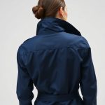 Back view of a model wearing a navy blue womens anorak jacket waterproof silver earrings, studio shot on white background.