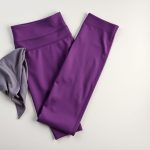 Flat lay of a Heather Grey yoga crop and purple yoga pants, neatly folded.