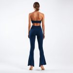 Back view of a model in a navy blue yoga crop and flared leggings on a white background.
