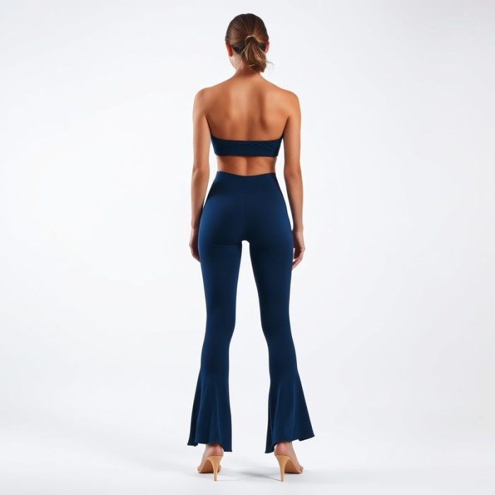 Back view of a model in a navy blue yoga crop and flared leggings on a white background.