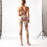 Back view of a model in a beige printed yoga crop and pants on a white background.